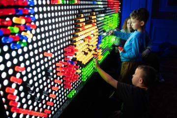 OHIO siblings move lit up, colorful pegs at the GLOHIO event in 2024